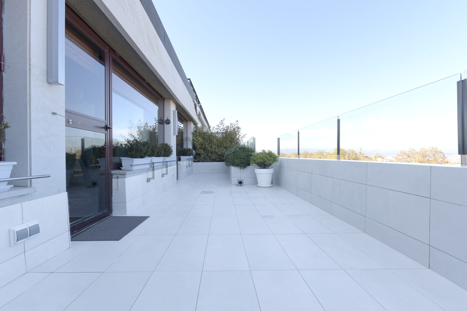 Proyecto de Rehabilitación de una terraza en un Ático de la céntrica calle Arrieta de Pamplona (Pamplona). Amplitud y vistas panorámicas seguras por la instalación de sobre barandilla de vidrio y luminosidad dad por las baldosas blancas.