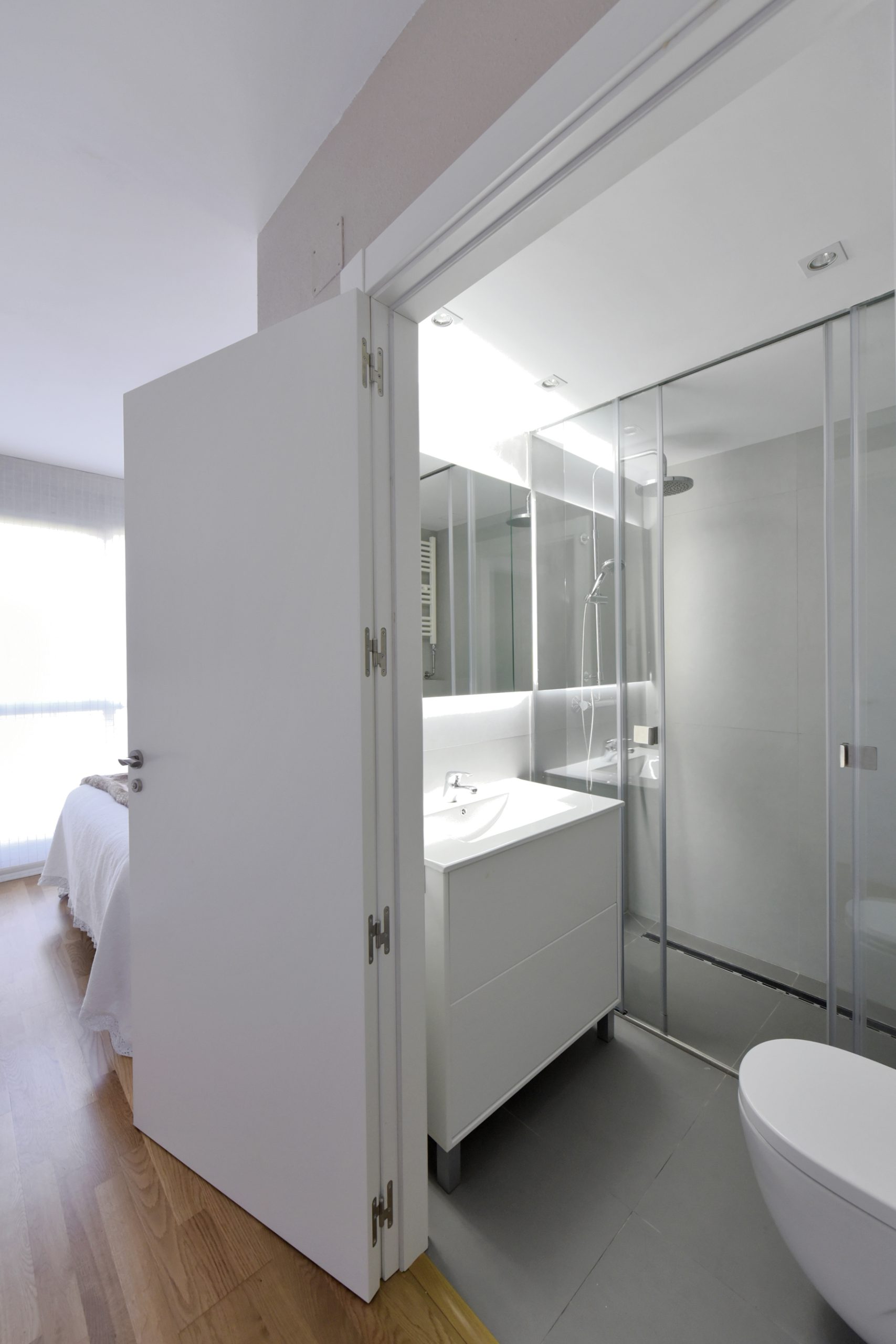 Proyecto de Reforma íntegra de baño en Zizur Menor (Navarra). Espacio pequeño iluminado con luz indirecta, donde el blanco es el único color para no agobiar. Diseño lineal, limpio y actual.