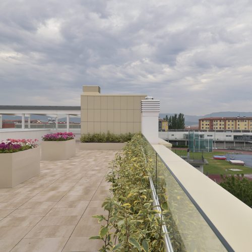 Proyecto de Rehabilitación de la Residencia San Fermín en Pamplona (Navarra). Terraza en el ático del edificio adecuada para dar paseos y sentarse en uno de los bancos instalados para disfrutar de las vistas panorámicas de las que posee este edificio.
