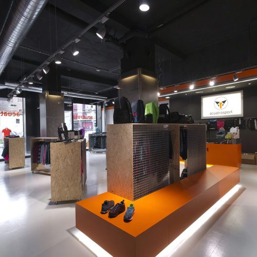 Proyecto de Reforma de local comercial para Acuatrosport en Burlada (Navarra). Decoración en tonos naranja y negro combinado con madera en un espacio amplio y diáfano.