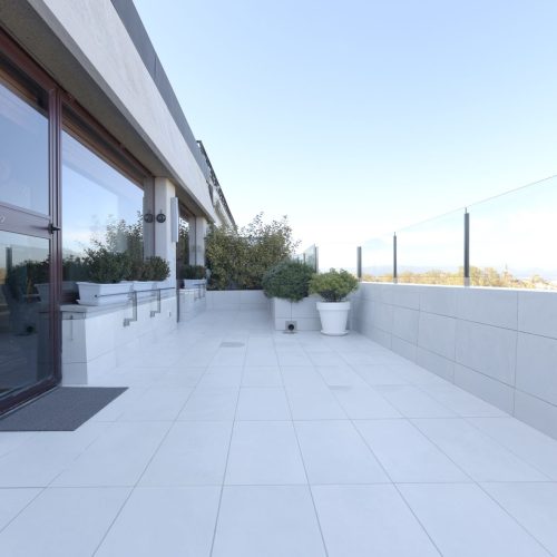 Proyecto de Rehabilitación de una terraza en un Ático de la céntrica calle Arrieta de Pamplona (Pamplona). Amplitud y vistas panorámicas seguras por la instalación de sobre barandilla de vidrio y luminosidad dad por las baldosas blancas.